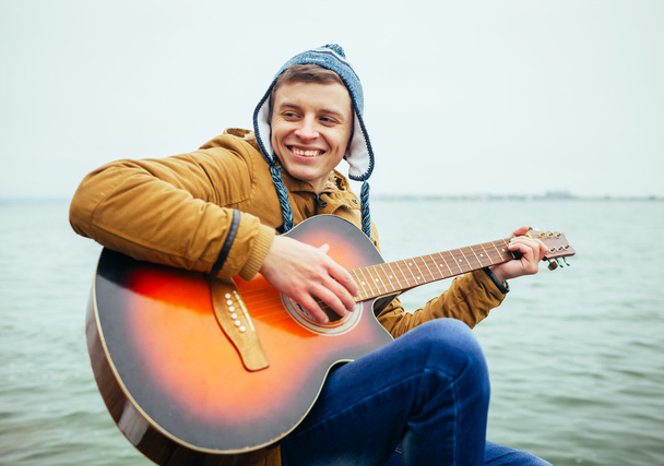man playing on guitar at the lake - Zdjęcie, obraz