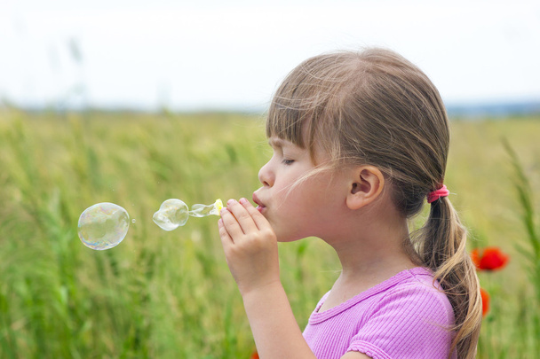 Porträt des niedlichen kleinen Mädchens, das Seifenblasen pustet - Foto, Bild
