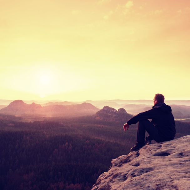 Турист сидит на скале и наслаждается весенним видом в горах
 - Фото, изображение