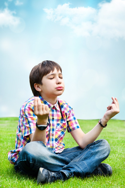 Photo of adorable young wise boy sitting on the grass at his bac - Foto, Imagen