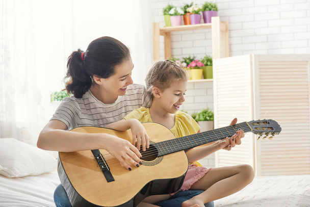 Mother and daughter playing guitar - 写真・画像