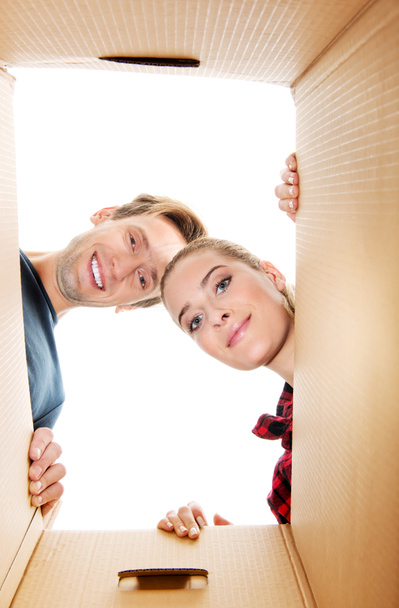 Heureux jeune couple ouvrant une boîte en carton et regardant à l'intérieur
 - Photo, image