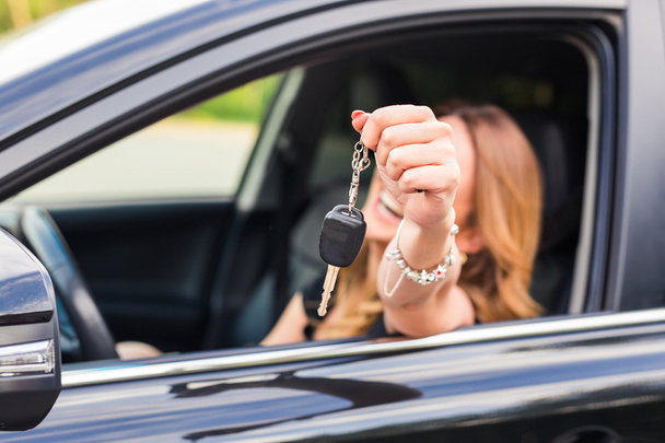 Mujer joven mostrando la llave en un coche
 - Foto, imagen