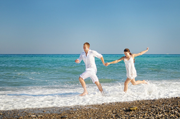 Feliz joven pareja corre habiendo unido las manos en la costa del mar
. - Foto, imagen