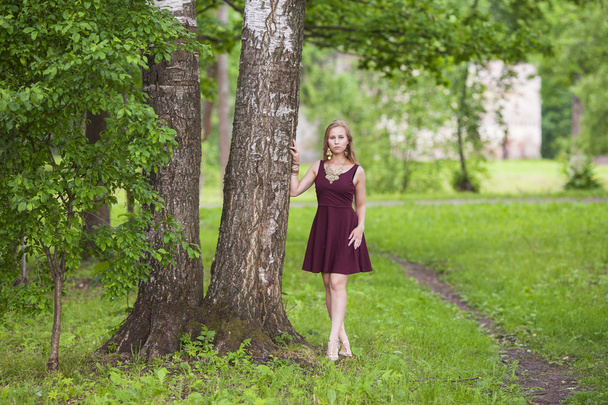 Girl in dress standing near a tree in the park - Fotó, kép