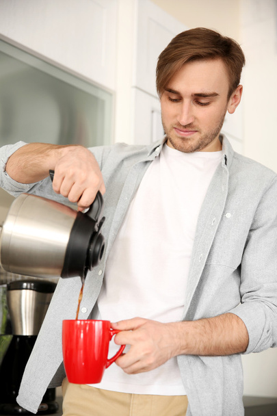 Young man pouring coffee into cup  - Foto, Bild