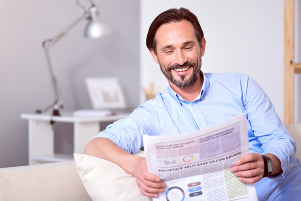 Чоловік читає газету на дивані
 - Фото, зображення