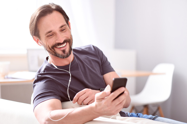Man using earphones and looking at phone - Photo, Image