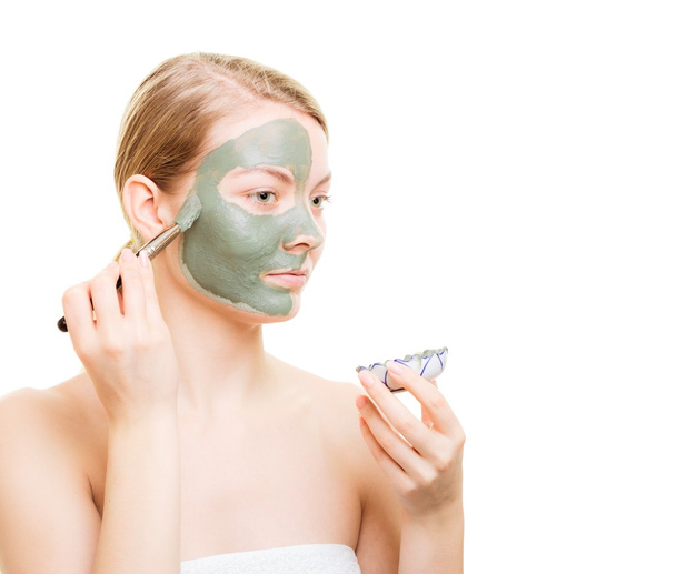 Girl applying facial clay mask to her face - Foto, Bild