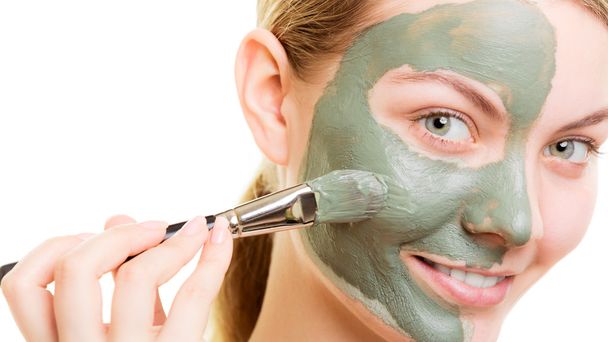 Woman applying with brush clay mud mask her face - Foto, Imagen