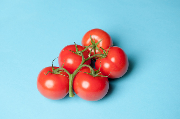 Viisi tuoretta tomaattia sinisellä pohjalla ylhäältä
 - Valokuva, kuva