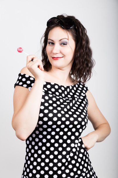 Portrait of happy beautiful young woman licking chupa chups. pretty woman with heart shaped lollipop - Foto, Bild