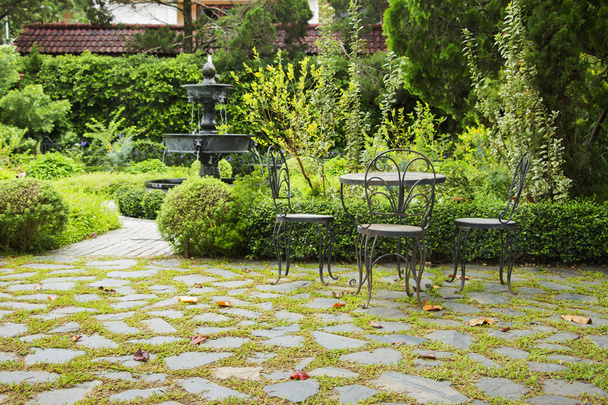 Strefa relaksu w ogród angielski. Krzesło z niewyraźne fontanna  - Zdjęcie, obraz