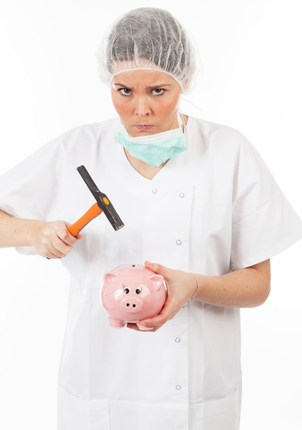 a woman doctor breaks his piggy bank with a hammer - Fotoğraf, Görsel