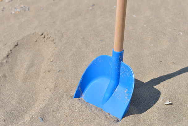 Blue shovel from plastic with wooden tail for kids in sand on a  - Foto, immagini