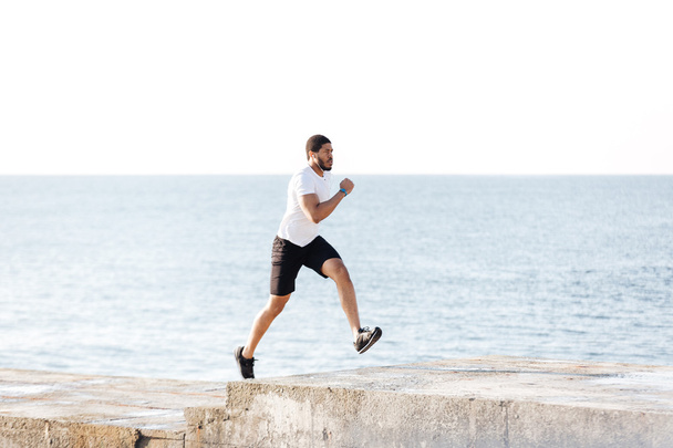 Handsome african sportsman running on pier - Valokuva, kuva