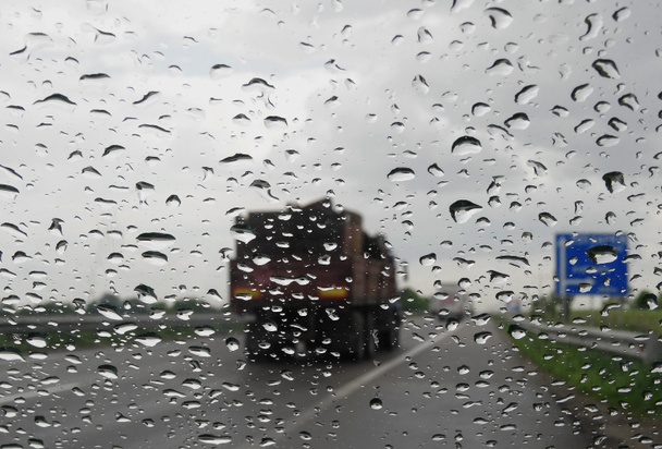 Σταγόνες στο παρμπρίζ του αυτοκινήτου στον αυτοκινητόδρομο στο βρέχει συνθήκες - Φωτογραφία, εικόνα