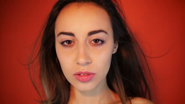 Portré imádnivaló szépség pózol míg elszigetelt vörös háttér - Felvétel, videó