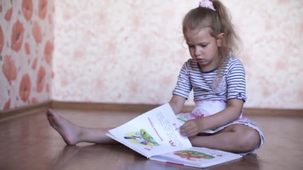 Маленькая девочка читает книгу, лежа на полу
 - Кадры, видео