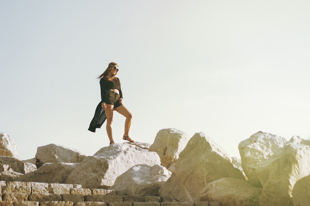 Jovem hippie fêmea em pé em grandes pedras
 - Foto, Imagem