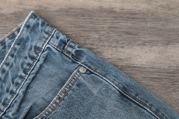 Синие джинсы на коричневом деревянном фоне
 - Фото, изображение