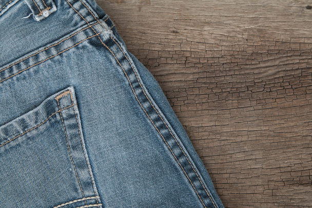 Blue jeans on a brown wooden background - Фото, изображение