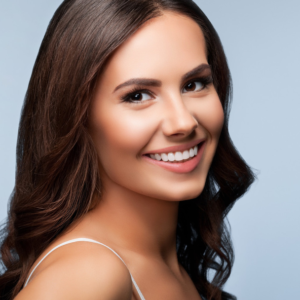 Portrait of smiling young woman, on grey - Fotoğraf, Görsel