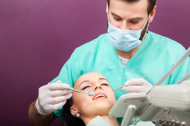 El dentista masculino examina la boca de la mujer en la silla del dentista
 - Foto, imagen