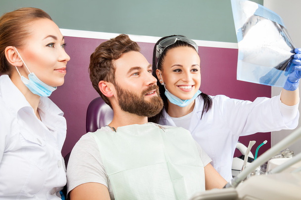 Le dentiste montre une radiographie des dents du patient
. - Photo, image
