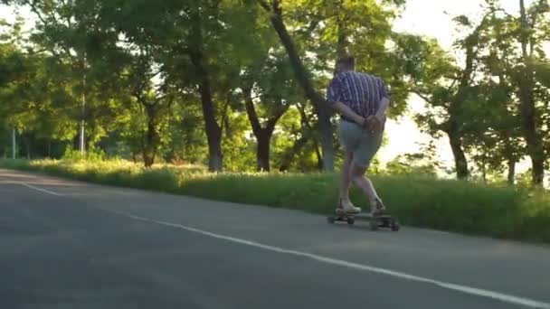 beau mâle équitation longboard dans le parc sur ensoleillé jour ralenti
 - Séquence, vidéo