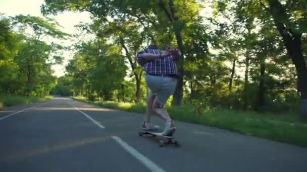πίσω όψη του ανθρώπου που ανέβηκε longboard στο πάρκο στην ηλιόλουστη μέρα αργή κίνηση - Πλάνα, βίντεο