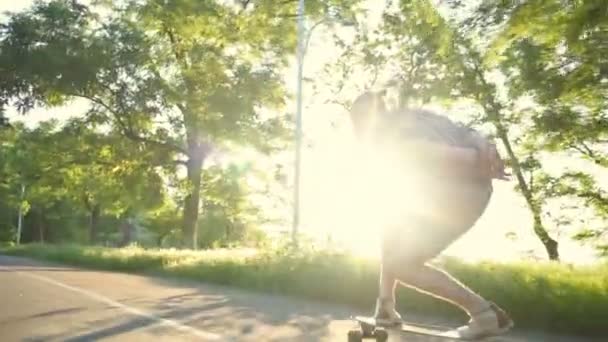 gutaussehender charismatischer Mann fährt Longboard und wendet sich der Kamera in Zeitlupe zu - Filmmaterial, Video