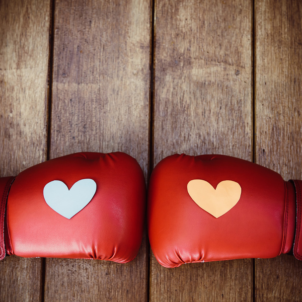 Hearts on red boxing gloves on wood. Conceptual image of fight f - Photo, Image