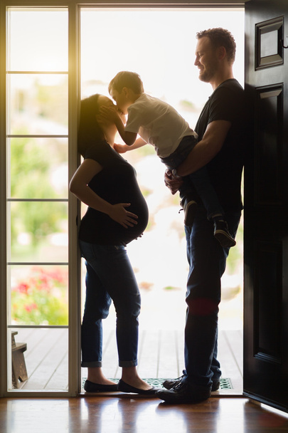 Joven hijo besando embarazada mamá con papá en puerta
 - Foto, Imagen