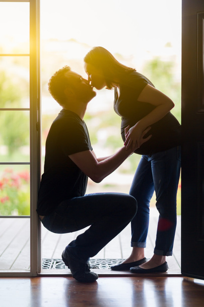 Sekarotuinen raskaana pari suudella oviaukossa
. - Valokuva, kuva
