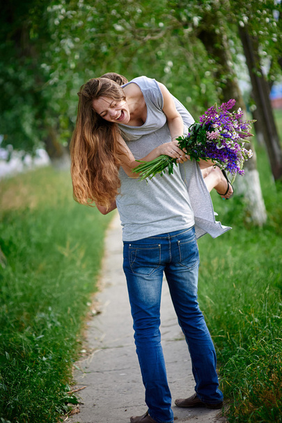 beautiful woman with a bouquet of lupine on the mans shoulder - Fotografie, Obrázek