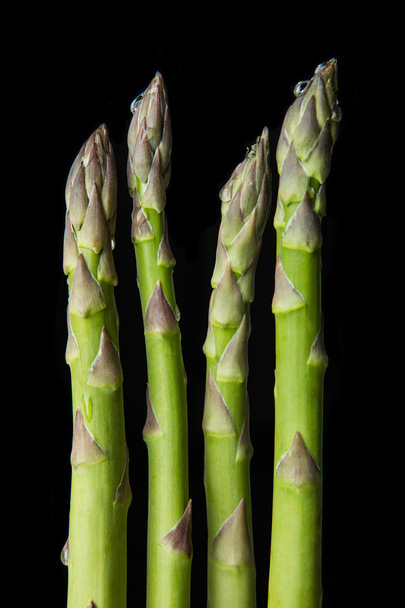 Raw asparagus on black background - 写真・画像