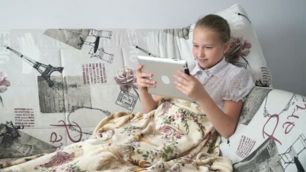 Child reading a digital tablet lying on the bed - Кадри, відео
