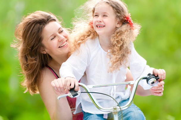 Jovem mãe e sua filha na bicicleta
 - Foto, Imagem