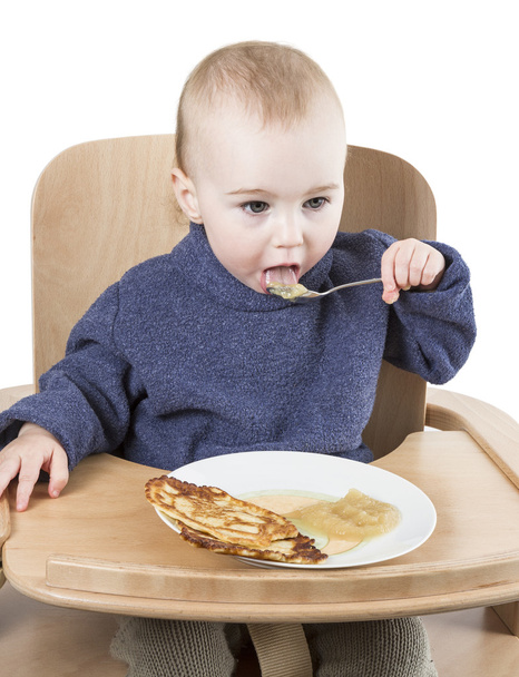Маленький ребенок ест в стульчике
 - Фото, изображение