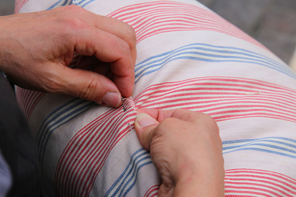 woman while sewing with needle and thread the pillow - Photo, Image