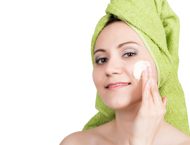 piękna młoda kobieta ubrana w ręcznik kąpielowy sprawia, że kosmetyk maski na twarzy. piękno przemysł i domu skóry opieki koncepcja. na białym tle - Zdjęcie, obraz