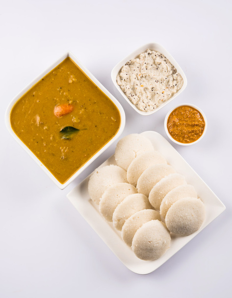 traditional south indian food, idli or idly with sambar and white coconut chutney and red chutney in white ceramic square plate and bowl on white background, front view isolated on white background - Photo, Image