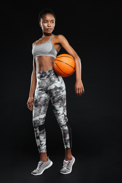 Full length portrait of a sports woman holding basketball ball - Foto, afbeelding