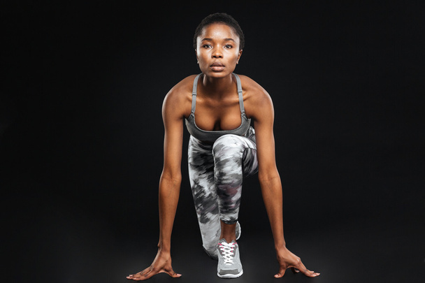 Full length of concentrated african american sportswoman over black background - Foto, Bild