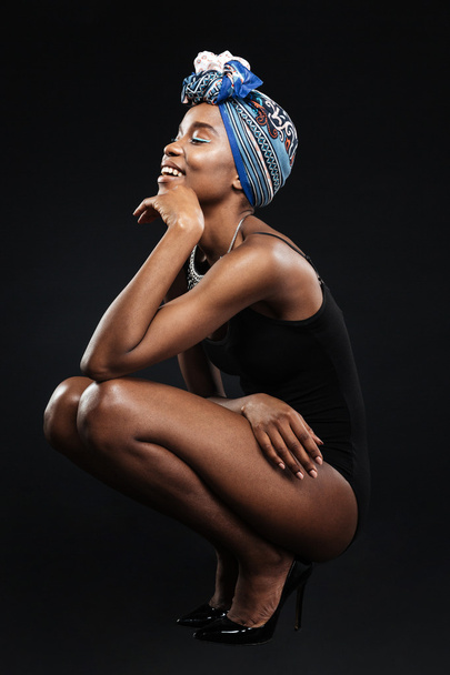 Beautiful smiling african woman in bodysuit posing in studio - 写真・画像