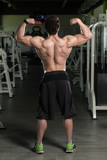 Muscular Man Flexing Biceps Muscles In Gym - Фото, изображение
