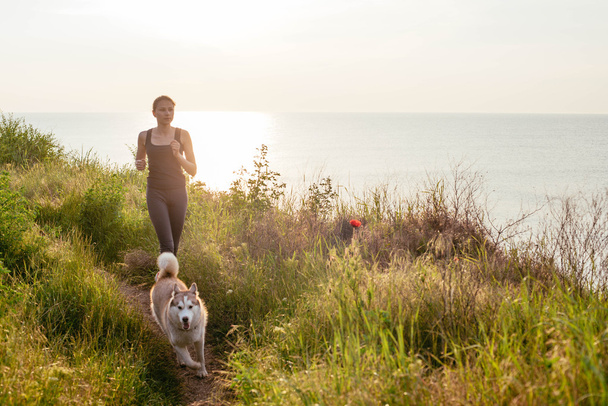 Woman and husky jogging in park - Фото, изображение