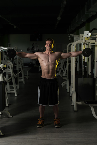 Young Man With Dumbbells Exercising Shoulders - Фото, зображення