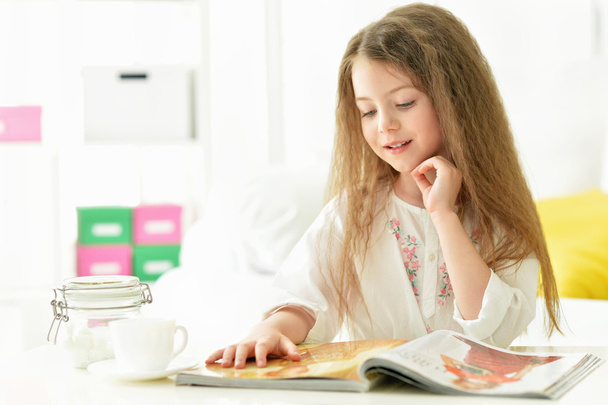 Beautiful little girl reading magazine  - Fotó, kép